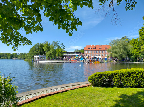 Serene lake scene with lush greenery and vibrant buildings, Szczecinek, Poland