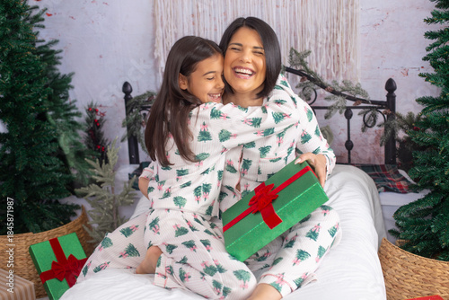 mom and daughter on a bed on Christmas morning giving a gift 