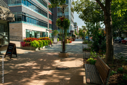 A shady side street with a welcoming bench lined with shops and buildings at the Cherry Creek North upscale Shopping District in Denver, Colorado.