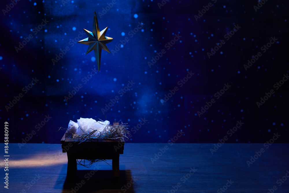 Obraz premium Starry Night Nativity. A nativity scene under a glowing star in a deep blue, starry background