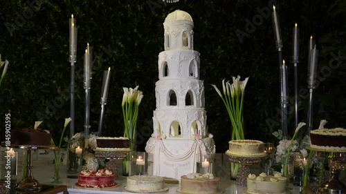 White wedding cake on a table with small cakes