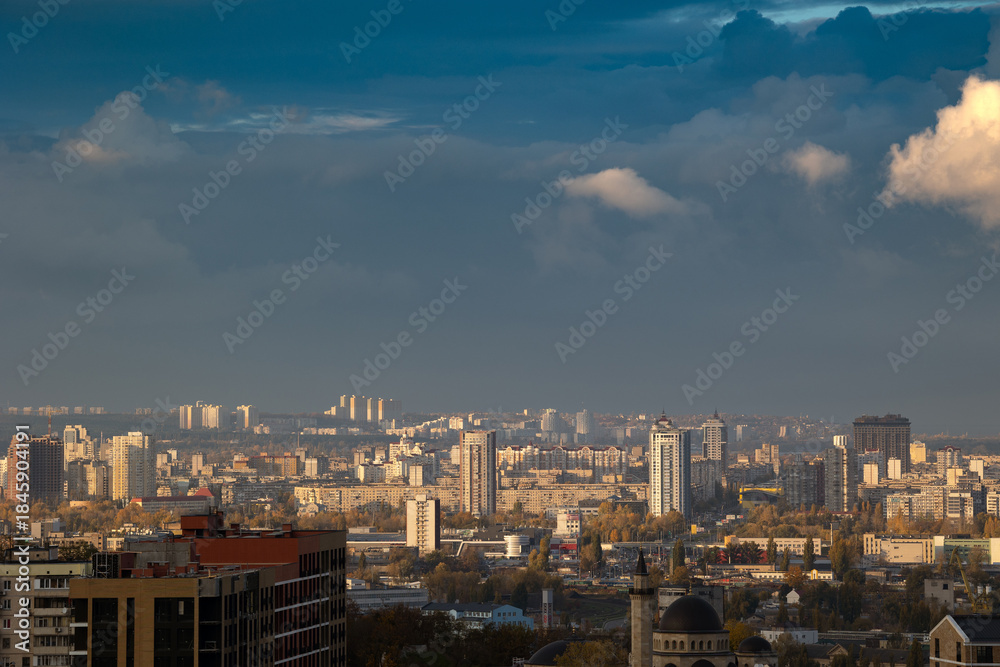Fototapeta premium Sunlit cumulus clouds over dense urban cityscape view