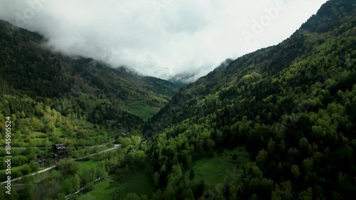 Scenic view of a verdant mountain valley in Andorra, covered in dense forest and shrouded in misty clouds, perfect for nature, travel, and adventure backgrounds.