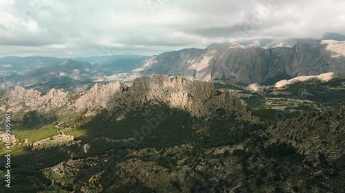 Aerial landscape of Puig Campana mountain in Costa Blanca, Spain, showcasing rugged peaks, lush forests, and dramatic clouds, ideal for travel, hiking, and nature backgrounds.