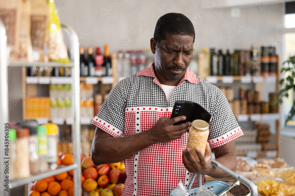 Fototapeta premium Adult male shopper scanning qr code for beans in jar in grocery store