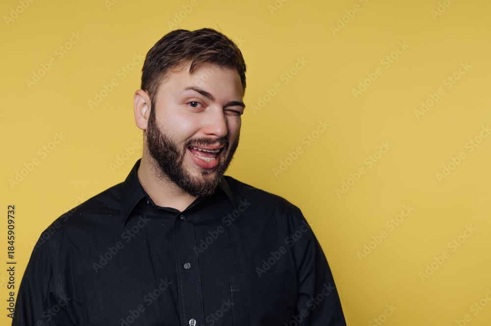 Obraz premium Man winks and smiles against a plain yellow background in a casual setting