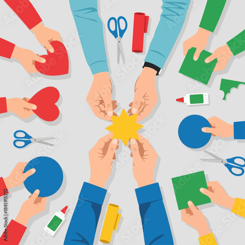 Many hands collaborating on a craft project with paper shapes, scissors, and glue on a table, illustrating teamwork and creativity.