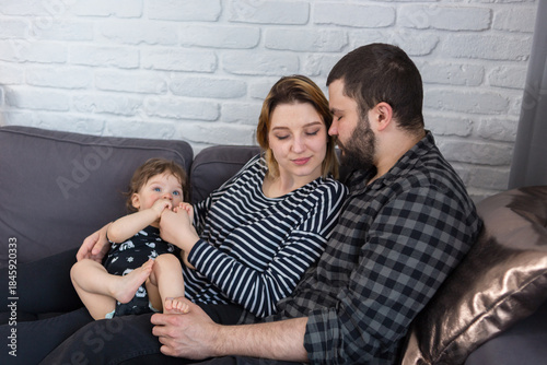 Young parents being affectionate while holding their 7-month-old infant son at home