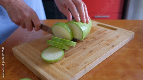 A woman and a man fry zucchini in a frying pan in an apartment in a darkened evening, preparing a raw product.