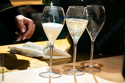 Pouring in glasses of french sparkling wine champagne with little bubbles, tasting wine, celebration, wedding or champagne tour with visit of caves, Reims, France