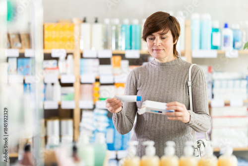 Woman in autumn clothes buys medicinal ointment at a pharmacy