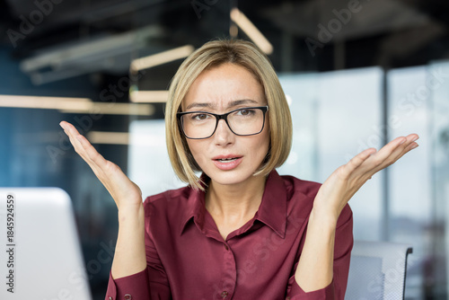 Tablou pe pânză Businesswoman shrugging with open hands and a puzzled expression, indicating dou