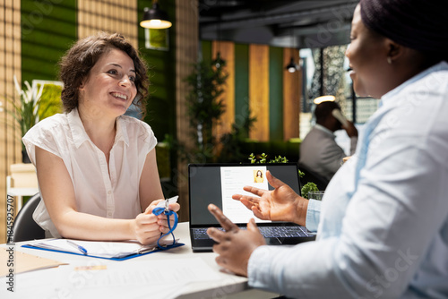 Photos Smiling female applicant receiving access security card from the HR manager during an onboarding interview, confirming employment approval and registration into the new workplace