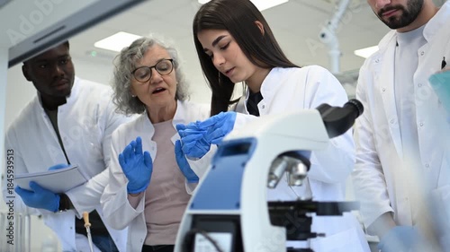 Senior scientist professor teaching students using microscope