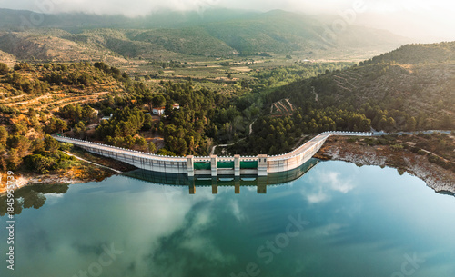 Stunning aerial photo of a dam and reservoir surrounded by lush hills in South Spain, ideal for illustrating water management, sustainability, and scenic landscapes.