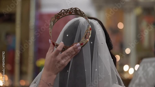 Bride Receiving Ornate Crown Over Veil In Church Crowning Ritual, Hand Placing Crown Glints With Jewels, Soft Candlelight And Ceremonial