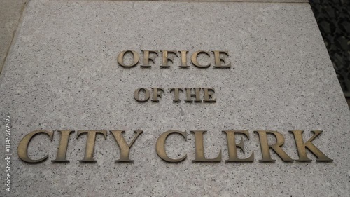Bronze City Clerk Letters On Stone Plaque, CloseUp Angled Composition Showing Embossed Lettering And Textured Concrete, Official Municipal