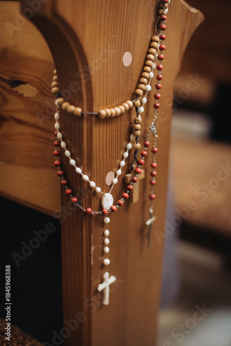 Rosaries hanging on wooden pew inside church