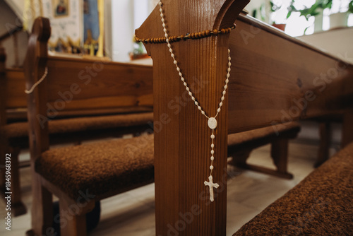 Rosary hanging on church pew during religious ceremony