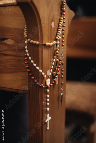 Rosaries hanging on wooden church pew