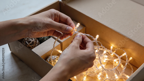 Hands preparing warm fairy lights for holiday decoration  
