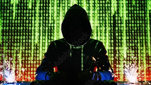 Silhouetted hacker in a hood, fists on a glowing keyboard amid cascading green binary rain at night