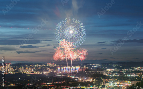 Foto Vibrant summer fireworks blooming in the blue hour sky above a city as evening transitions into night