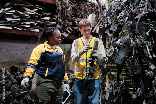 White male worker checks auto spare parts stock storage with Black female inspector at stack warehouse, working labor job in manufacturing factory, and industrial occupation for distribution business.
