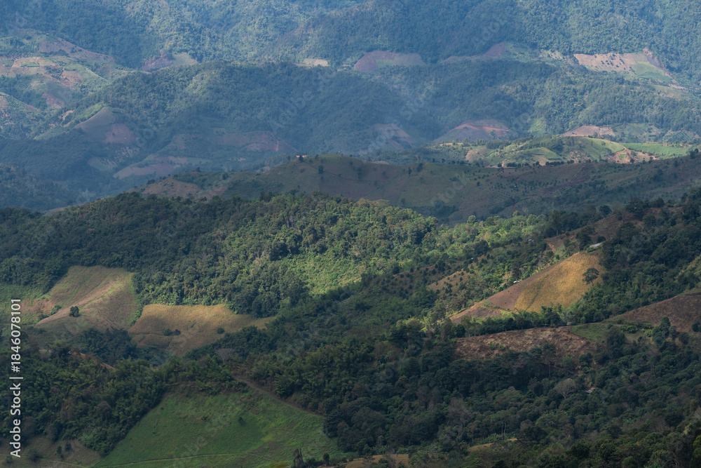 Obraz premium Majestic Mountain Landscape Showcasing Lush Green Terrains, Rolling Hills, and Dramatic Shadows under a Bright Sky in Remote Highlands