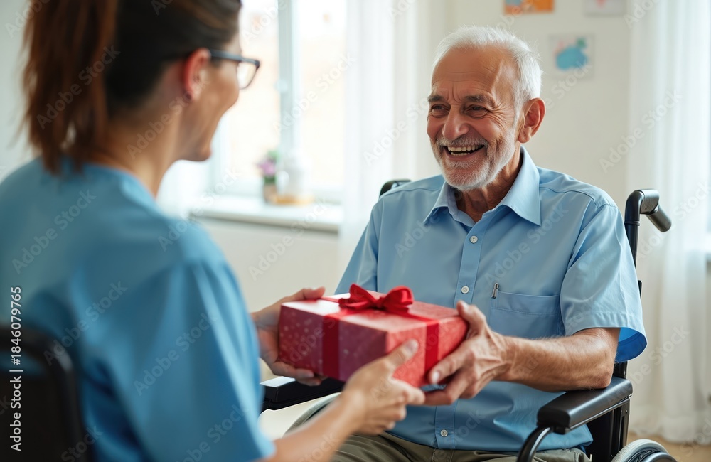 Obraz premium Caregiver gives gift box to smiling senior man in wheelchair. Elder receives present with joy on birthday or holiday occasion. Helping hand for elderly person.