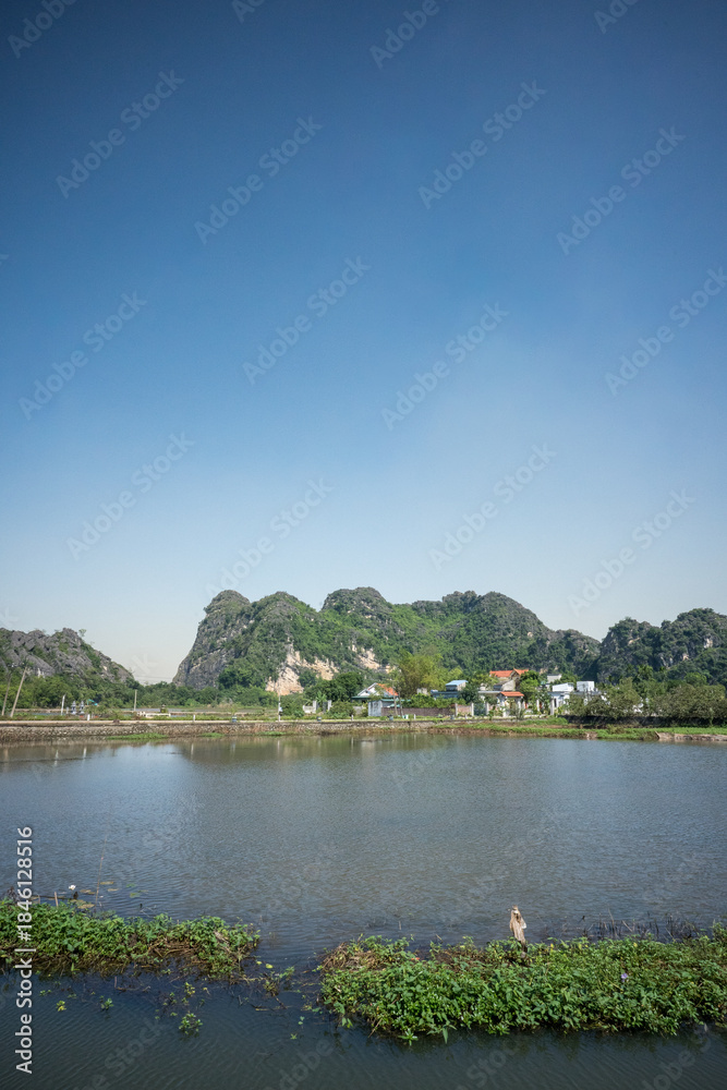 Fototapeta premium Rural Landscape with Limestone Mountains and Water Pond in Ninh Binh, Vietnam