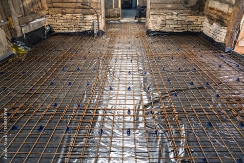 Fotografie Preparation for pouring a reinforced concrete floor slab with a rebar grid on a protective plastic membrane, ensuring structural integrity for robust buildings and infrastructure