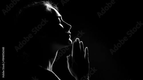 Silhouette of a woman praying with hands pressed together at sunset, expressing faith, hope, spirituality, and peaceful devotion in a serene atmosphere.