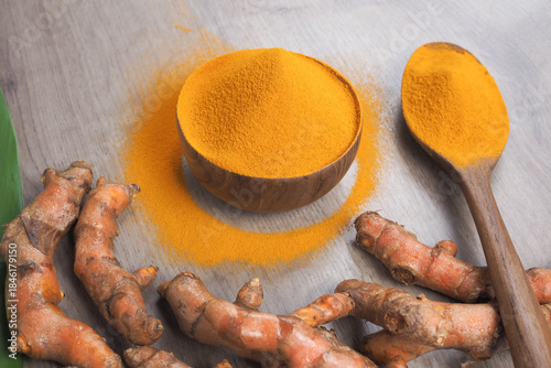 Turmeric Powder and Fresh Turmeric Roots on Wooden Background