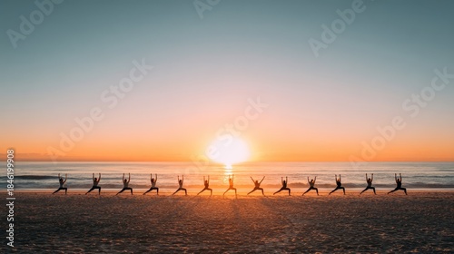 Silhouetted group performing yoga poses on a sandy beach at a vibrant sunset over the ocean.