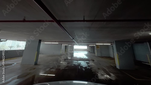 The multilevel parking garage lot at the modern building. Car moves inside the building along parked cars.