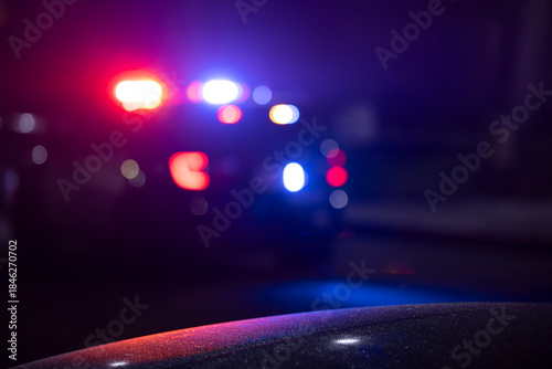 Abstracted illuminated night view of police units on a city street.
