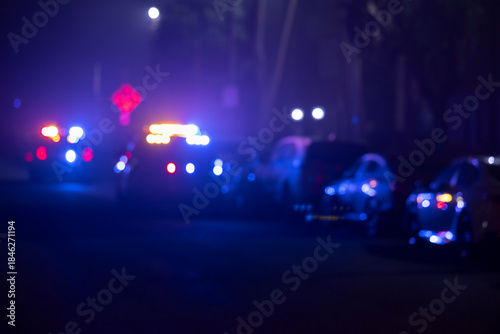 Abstracted illuminated night view of police units on a city street.
