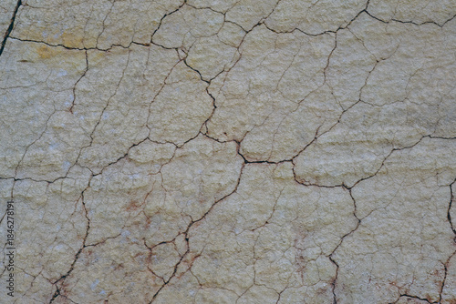 Close-up of natural stone surface texture with cracks and weathered details. Abstract rocky background showing aged mineral patterns and rough stone structure.