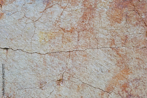 Close-up of natural stone surface texture with cracks and weathered details. Abstract rocky background showing aged mineral patterns and rough stone structure.