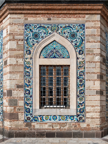 Intricate tile work adorns the exterior of Izmir Konak Mosque, showcasing arched window adorned with vibrant patterns and mosaic craftsmanship. Located in bustling Konak Square, in Izmir, Turkey