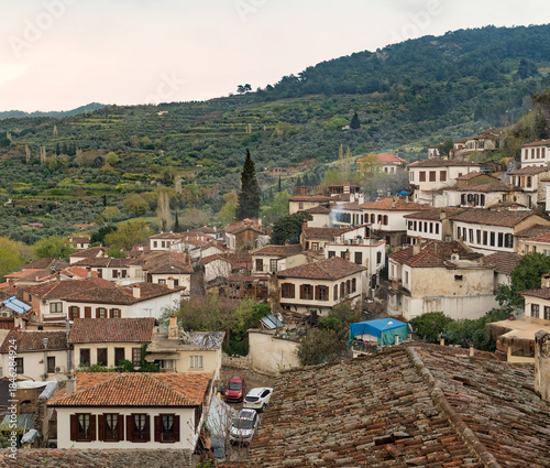 Scenic sunset over the historic village of Sirince, Turkey. Traditional Ottoman houses with red tile roofs are nestled in the lush green hills of the Izmir province