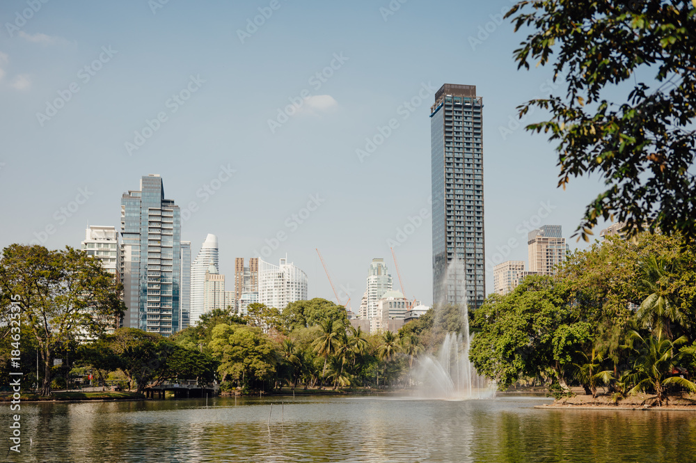 Fototapeta premium Lumpini Park Lake with Fountain and Modern Bangkok Skyline