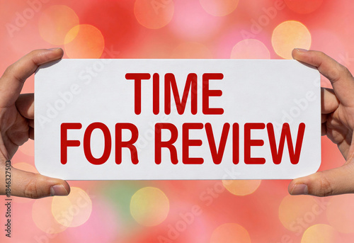 It is time for review with happy new year in background of red bokeh lights held in person hand on white sheet of paper concept