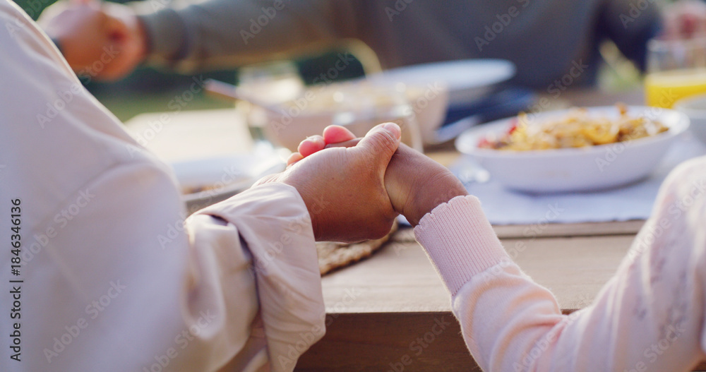 Obraz premium Lunch, backyard and family holding hands by table to pray at celebration, gathering and festive dinner. Christmas, closeup and parents with child with faith, religion and grace for meal in holiday