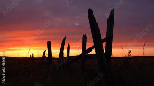 Rustic fence silhouette against a vibrant sunset sky at dusk