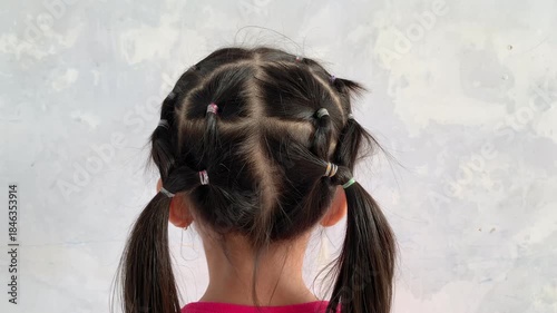a kid with hair tied braided from behind.