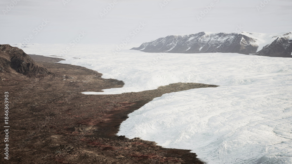 Obraz premium A breathtaking scene unfolds as a massive glacier stretches across the land, contrasting with the rocky terrain. The soft light of dawn illuminates the icy surface and nearby mountains.