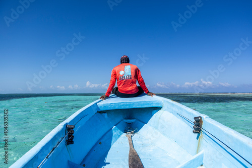 Man sits on bow of a boat, heading out to go fishing