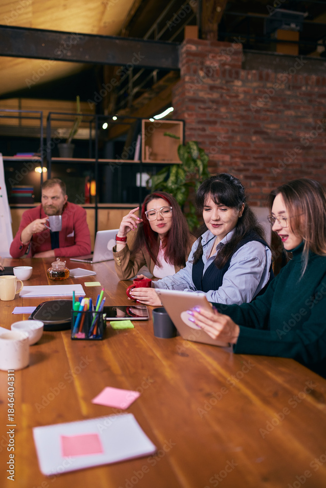 Obraz premium Creative team working together at modern coworking table. Concept of collaborative office culture, teamwork workflow, shared ideas, creative business environment and productive meeting.